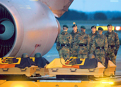 Vom Flugzeug werden die Särge von Soldaten durch ein Fackelspalier getragen.